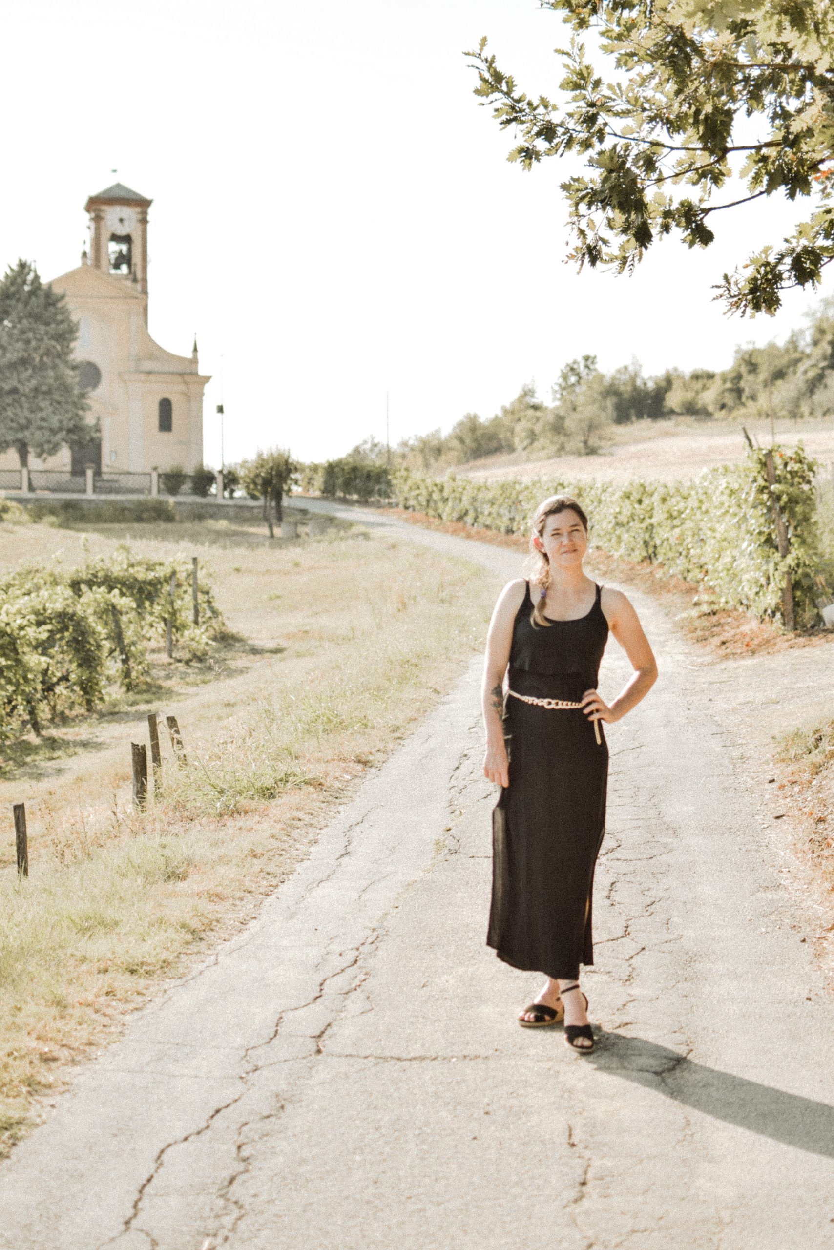 girl standing in the langhe italy black dress with church in background first steps move to italy