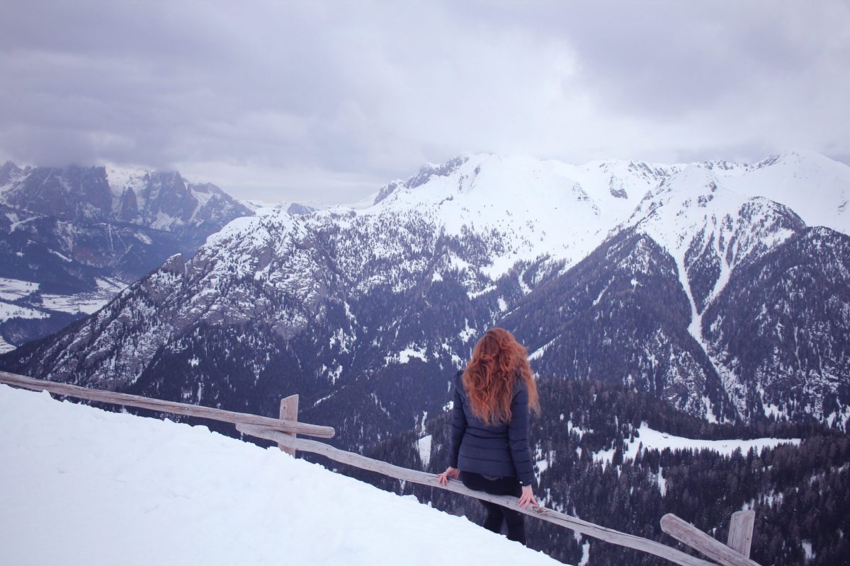 girl with read hair looking over the snowy dolomite mountains of Italy in January