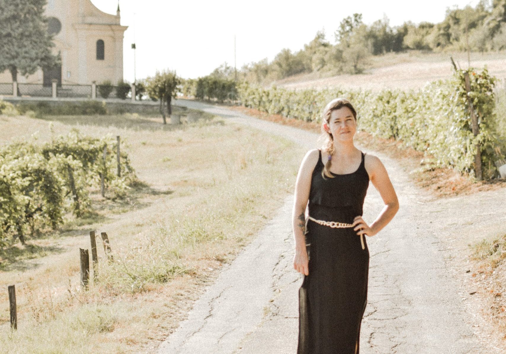 girl standing in the langhe italy black dress with church in background first steps move to italy